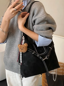 Versatile black shoulder bag with white contrast stitching, studs, and a cute bear charm