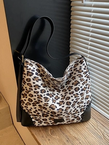 Retro large leopard print tote bag with black leather stitching on a wooden windowsill
