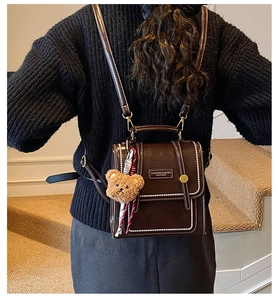 Détail du sac à dos en cuir PU marron foncé avec coutures blanches et petit ours