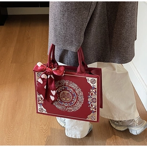 Détail du sac de mariée rouge avec broderie Double Bonheur dorée et écharpe à cœur
