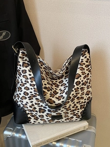 Large leopard print tote bag with black leather trim on a silver suitcase for travel