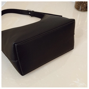 Detail view of black pebble leather tote bag with silver buckle and fine stitching