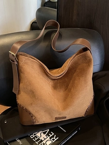 Large brown suede hobo bag with leather trim on a leather chair, retro winter style