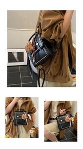 Detail view of black PU leather mini backpack featuring white stitching and bear charm