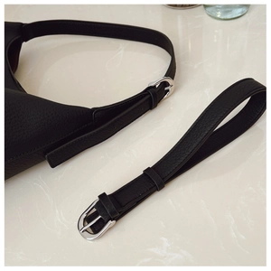 Detail of silver pin buckle and pebbled leather texture on black shoulder bag strap