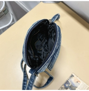 Detail view of denim crossbody bag interior with blue lining and storage pocket
