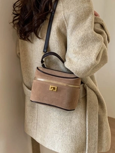 Sac boîte en daim marron avec détails dorés vintage et garniture en cuir porté sur manteau beige