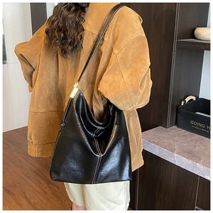 Détail du sac hobo en cuir brillant noir avec surpiqûres contrastées et boucles dorées