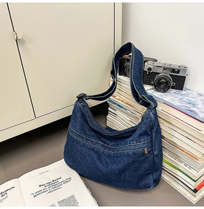 Detail view of dark blue denim hobo bag featuring decorative stitching and crescent shape