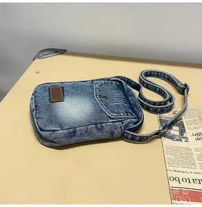 Close-up of retro washed denim crossbody phone bag with leather patch and adjustable strap