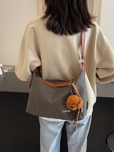 Large dark grey canvas tote bag with brown trim and cute teddy charm, worn cross-body