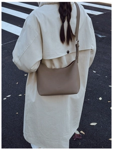 Minimalist brown pebbled leather crescent hobo bag worn by model in city street