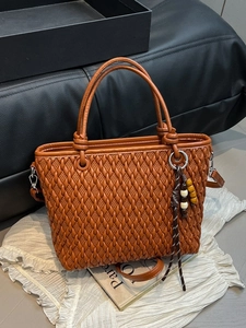 Caramel brown woven bucket bag with top handle and detachable strap on white display