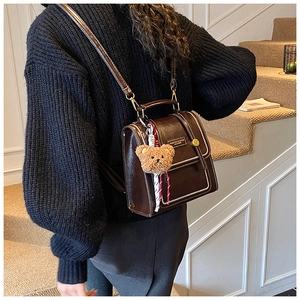 Détail d'un sac à dos vintage en cuir marron foncé avec finitions dorées et ourson