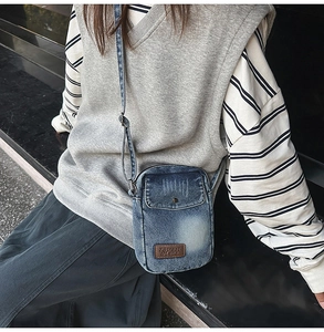 Close-up of vintage washed denim crossbody bag with adjustable strap and brand tag