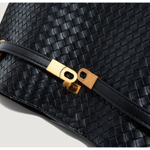 Close-up of black woven leather texture and vintage gold metallic clasp on tote bag