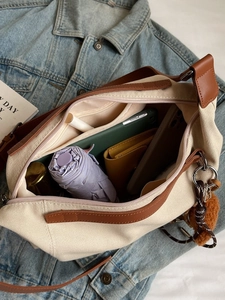 Spacious off-white canvas crossbody tote with brown leather trim and internal storage
