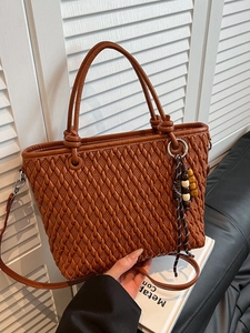 Brown woven bucket bag with wood bead charm and adjustable strap for elegant daily commute