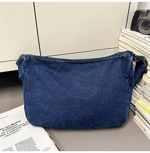 Detailed view of dark blue denim shoulder bag featuring yellow contrast stitching and soft fabric
