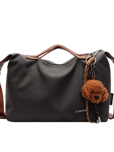 Spacious grey canvas tote bag with brown leather handles and plush charm for casual commuting