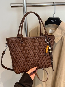 Dark brown quilted bucket bag with cylindrical handles and a colorful beaded tassel charm