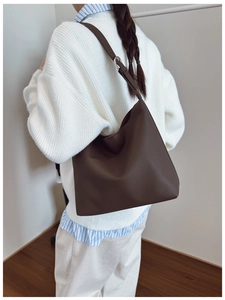 Close-up of brown pebbled leather hobo bag showing texture and adjustable wide shoulder strap