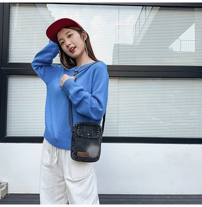 Outdoor lifestyle shot of a navy denim mini crossbody bag with leather patch detail