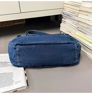 Detail view of denim shoulder bag rectangular bottom with contrast stitching and texture
