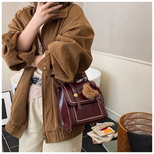 Détail du sac bandoulière bordeaux vintage avec coutures blanches et boucle d'or