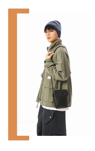 Detail view of a black mini crossbody bag with double snap buttons on a street style model