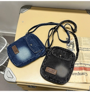 Detail of vintage denim crossbody bags in blue and charcoal on a retro suitcase