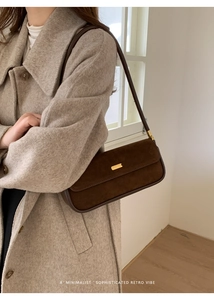 Nahaufnahme einer braunen Wildleder-Achseltasche mit goldener Schnalle zum Tweed-Mantel
