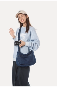 Detail of dark blue denim hobo bag with wide shoulder strap and contrast stitching
