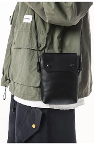 Detail view of black leather mini crossbody phone bag with snap buttons on model