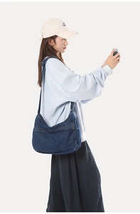 Detail view of deep blue denim crossbody bag with adjustable strap worn by a model