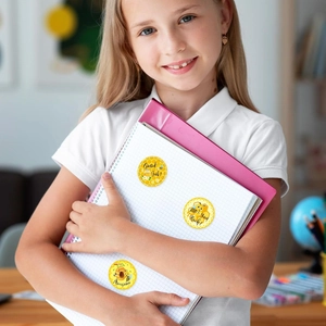 Close-up of a girl holding school notebook with cute bee reward stickers in yellow