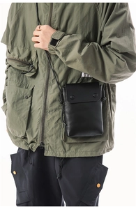 Detailed view of black leather mini crossbody phone bag with two metal snap buttons