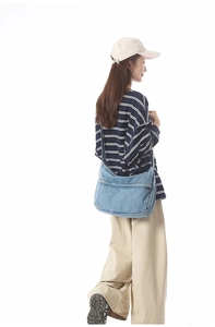 Blue denim crossbody bag featuring a large zipper pocket and adjustable shoulder strap
