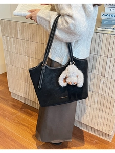 Detail of black suede tote bag with contrast white stitching and plush bunny pendant