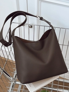 Deep brown pebbled leather tote bag with wide adjustable strap on a modern display