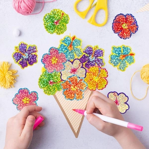 Macro view of colorful hibiscus glitter stickers on kraft paper with craft tools around