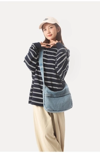 Lifestyle shot of light blue denim crescent crossbody bag on a casual striped outfit
