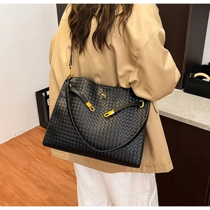 Macro shot of black woven leather tote texture with luxury gold metal hardware buckle