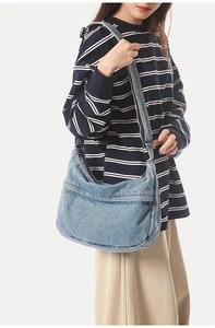 Detail of light blue washed denim hobo shoulder bag with functional front zipper pocket