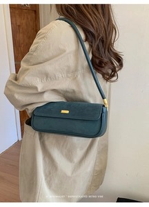 Détail du sac sous l'aisselle en daim vert foncé avec boucle dorée sur trench