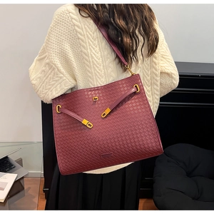 Close-up of wine red woven leather tote bag with gold buckle hardware and texture