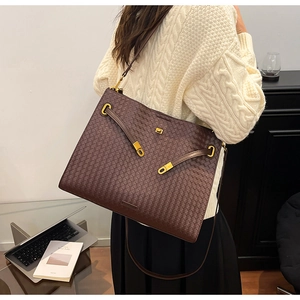 Close-up of dark brown woven leather tote with intricate texture and gold hardware details