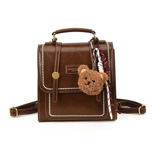 Retro brown leather backpack with white stitching and cute plush bear charm for women