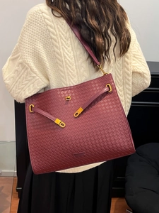 Burgundy woven leather tote bag with gold hardware and intricate textured craftsmanship