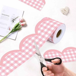 Pink and white checkered wavy bulletin board border stickers being cut for DIY classroom decor